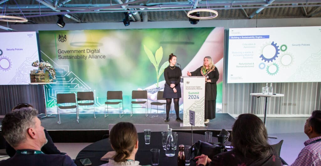 Two female presenters on stage at an event.